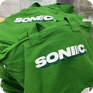 Custom screen printed green tote bags with multicolored Sonic logo for merch drop