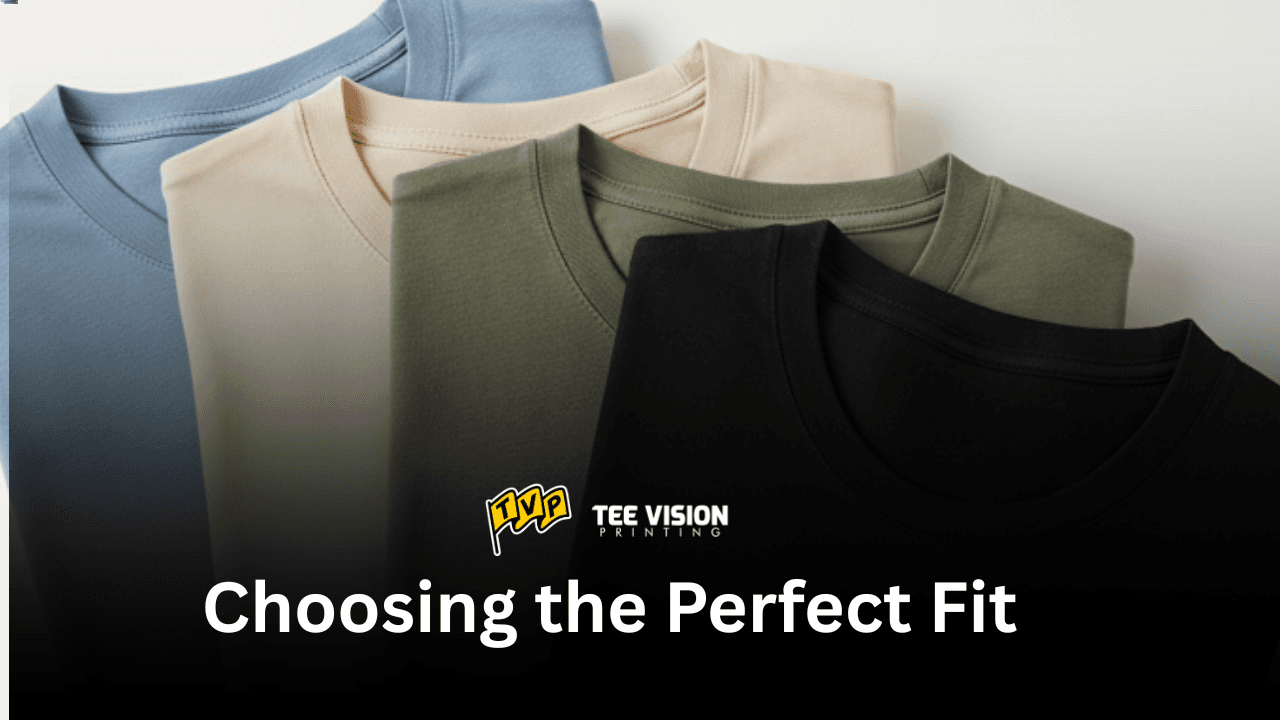 Four folded t-shirts in different colors—blue, beige, green, and black—with the text 'Choosing the Perfect Fit', illustrating the variety of options to consider when deciding which fit style is best for your merch.
