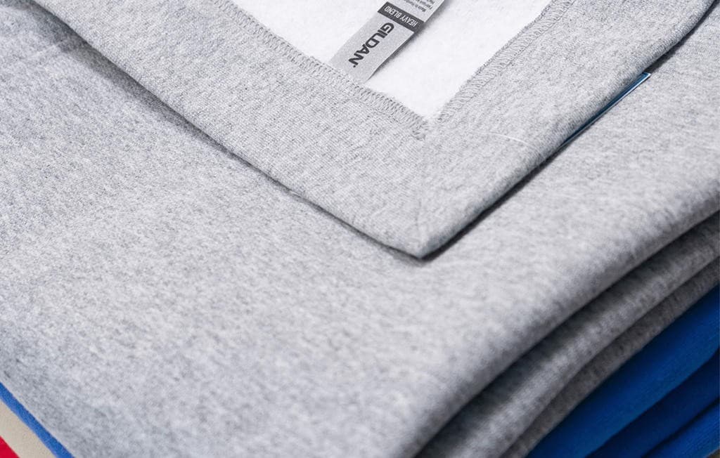 Folded Gildan fleece hoodies in neutral tones, showcasing top picks for fleece hoodie printing in your seasonal fabric guide for custom fall merchandise.