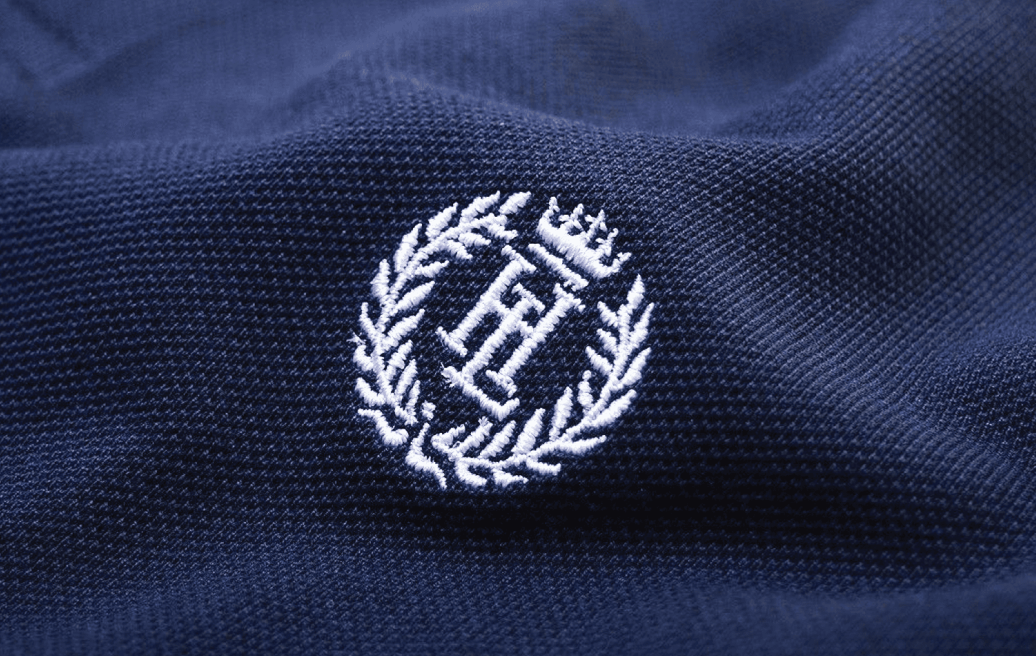Embroidery vs. Screen Printing comparison—detailed embroidered emblem on textured fabric highlights the premium, dimensional quality of stitched logos.