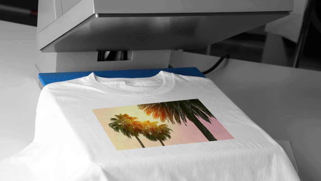 A white t-shirt with a palm tree graphic on a heat press, ready for custom t-shirt silk screen printing.