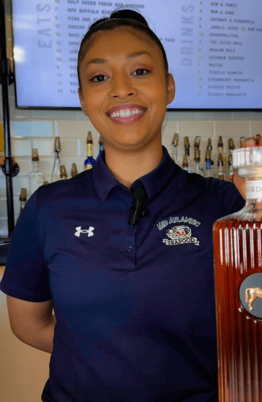 Restaurant staff member wearing a branded navy polo shirt, showcasing how custom restaurant staff uniforms contribute to restaurant branding through uniforms and transform uniforms into wearable brand merchandise.