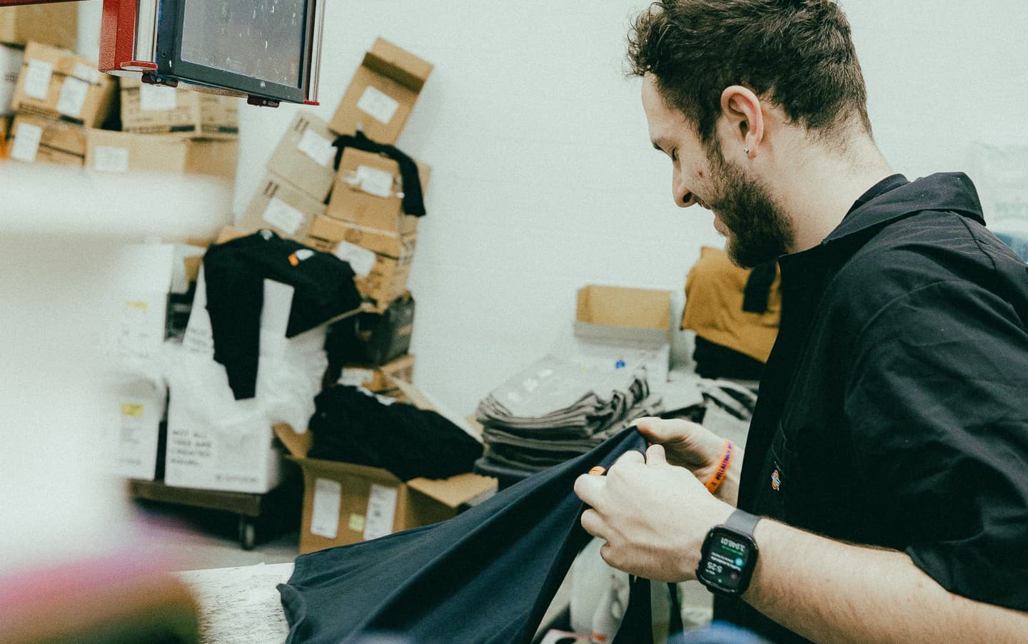 A worker in a clothing workshop handling garments illustrates the production side of what is puff printing. This behind-the-scenes view connects to screen printing techniques, showing how puff ink screen printing is applied to create raised ink printing for custom puff apparel.