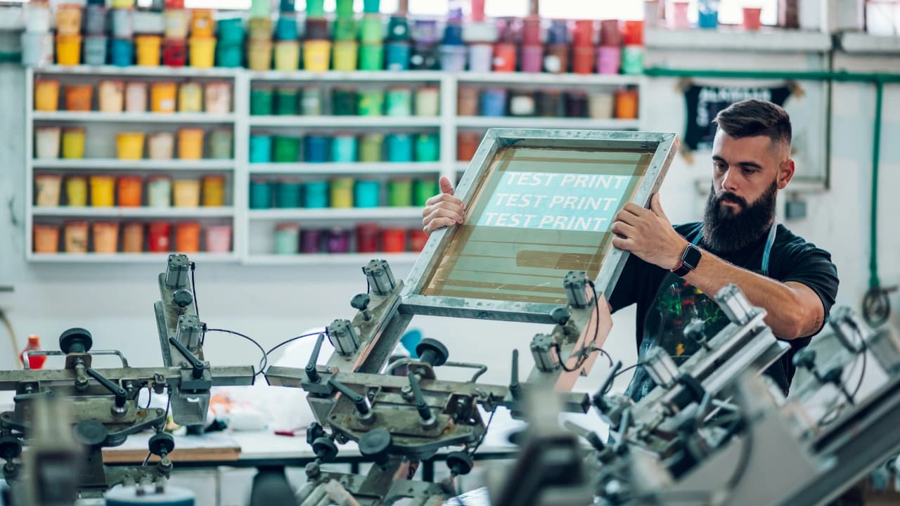 An expert sets up a test print for a custom t-shirt design wholesale order, ensuring perfect silk screen results.