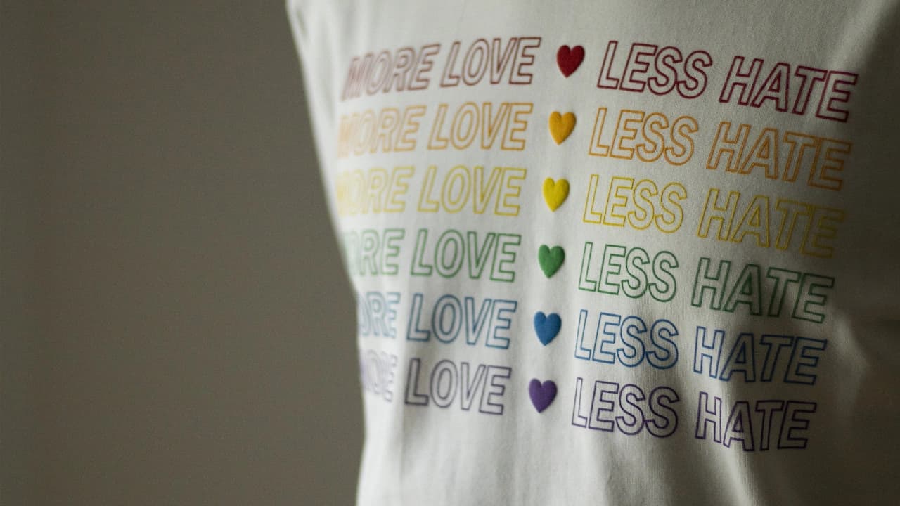 Close-up of a t-shirt with "MORE LOVE LESS HATE" in rainbow colors, showcasing custom t-shirt design.
