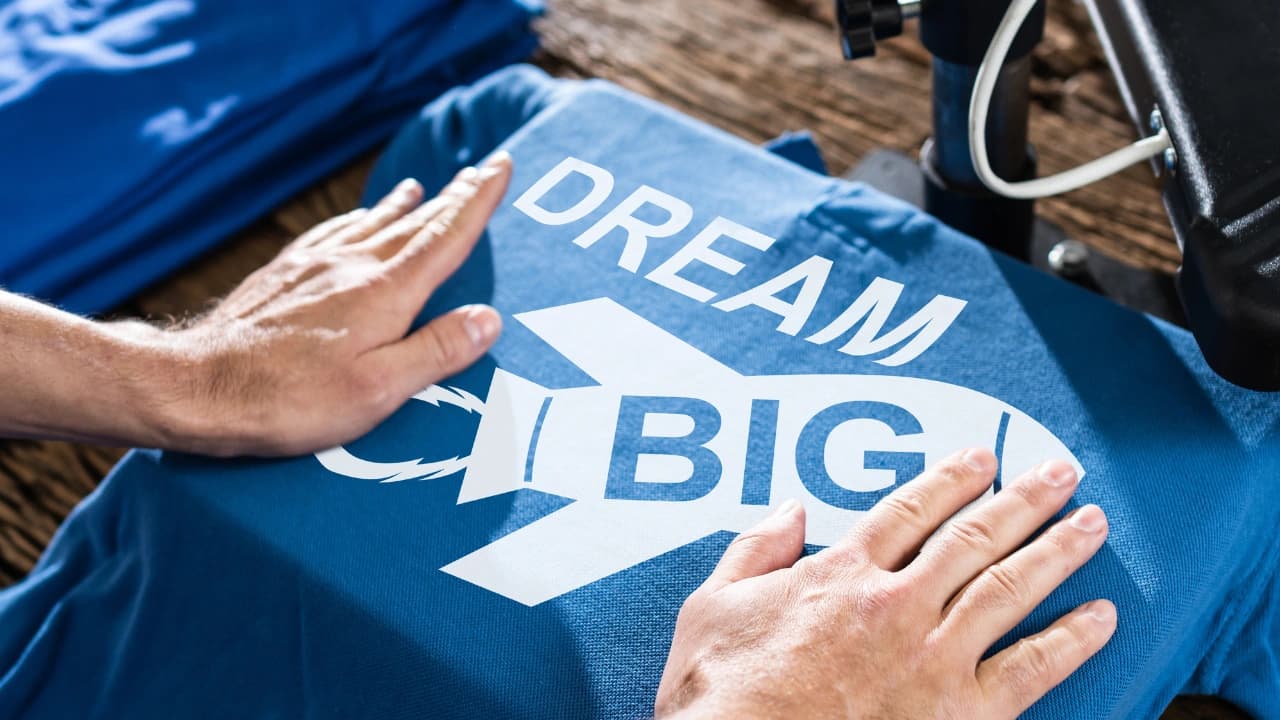 Our apparel design services create inspiring graphic design apparel like this 'Dream Big' airplane-themed blue t-shirt.