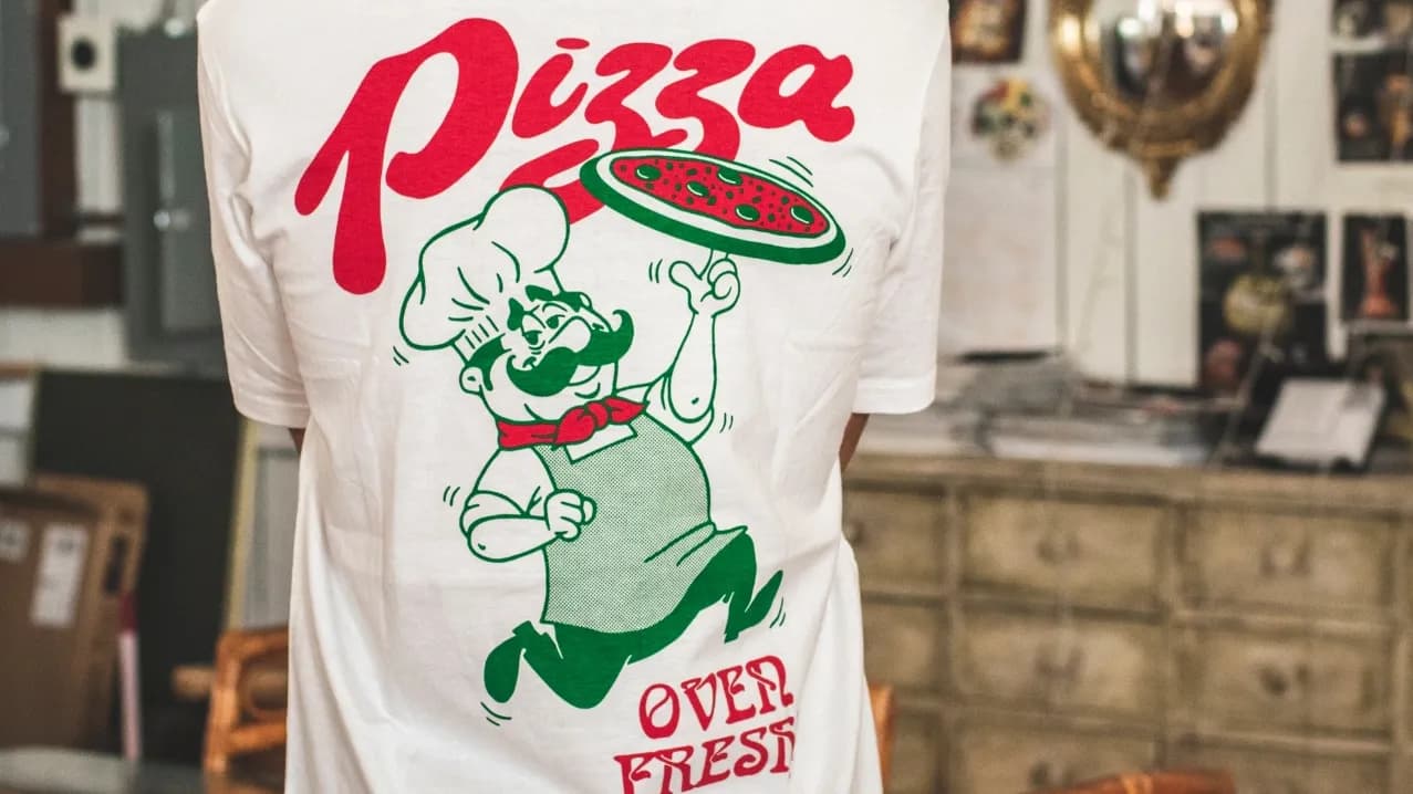 Example of our graphic design apparel featuring a retro pizza chef, made with vibrant personalized screen printing.