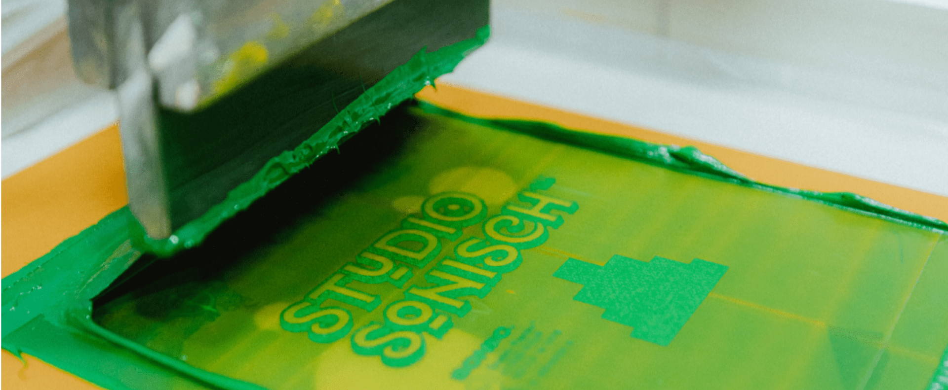 Screen printing a green design on a t-shirt, highlighting custom t-shirt design and silk screen printing.